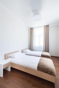 2 camas en un dormitorio con paredes blancas y suelo de madera en Black Pearl Apartments en Jūrmala