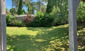 einen Hof mit grünem Gras und einer Holzpfähle in der Unterkunft Ohana House w Juracie in Jurata