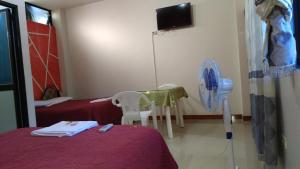 Cette chambre comprend deux lits, une table et un ventilateur. dans l'établissement Hostal Nuevo Amanecer, à El Coca