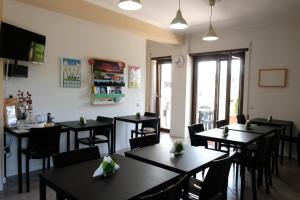 un restaurante con mesas negras, sillas y ventanas en B&B Grandangolo, en Preturo