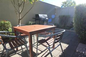 een houten tafel met 2 stoelen en een grill bij Alpine Lake Motel in Taupo