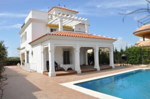 ein weißes Haus mit einem Pool davor in der Unterkunft Villa Canela with Heated Pool, Piscina Climatizada in Isla Canela