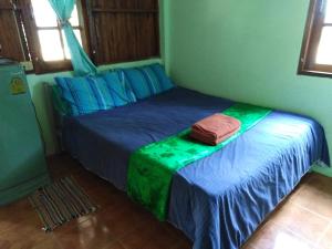 a bedroom with a bed with blue and green sheets at Mountain View Guesthouse in Sukhothai