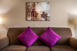 a couch with two purple pillows sitting under a painting at Grand Legacy At The Park in Anaheim