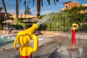 a yellow fire hydrant spewing water into a pool at Grand Legacy At The Park in Anaheim