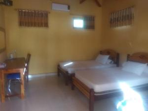 a room with two beds and a table and a desk at Ocean holiday in Bira