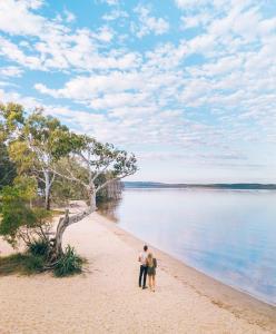 a person standing on a beach next to a body of water at Habitat Noosa in Cootharaba