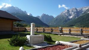 a stone monument in front of a fence with mountains at Apartments Sunseit'n in Sesto