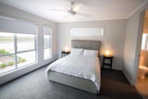 a bedroom with a bed with two night stands and two windows at Wellington Lake Retreat in Wellington East