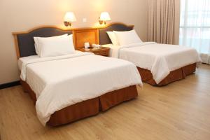 Habitación de hotel con 2 camas con sábanas blancas en Mega Hotel, en Miri