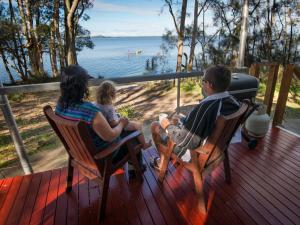 un hombre y una mujer sentados en una cubierta con un niño en NRMA Myall Shores Holiday Park, en Bulahdelah