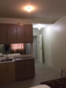 a kitchen with wooden cabinets and a sink in a room at Staycation condo with pool near SM Tungko, Bulacan in Mangangpico