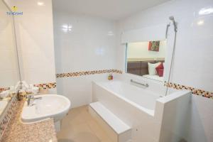 a white bathroom with a sink and a tub and a mirror at Taragrand Donmuang Airport Hotel in Thanyaburi +38 photos