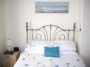 ein Bett mit weißer Bettwäsche und einem blauen Kissen darauf in der Unterkunft Causeway Holiday Homes in Coleraine