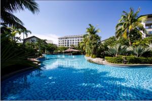 a large swimming pool with palm trees and a building at Mingshen Golf & Bay Resort Sanya in Sanya