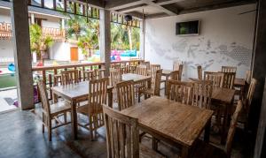 an empty restaurant with wooden tables and chairs at Kaniu Lombok Hostel in Kuta Lombok
