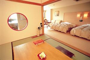 a room with a table and a bed and a mirror at Hotel Kanronomori in Niseko