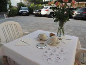 Una mesa blanca con un jarrón de flores. en Hotel ai Fiori, en Grado