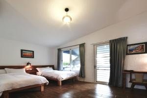 1 dormitorio con 2 camas y ventana en Lan People Villa, en Hai-liao