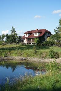 uma casa sentada numa colina ao lado de um lago em Gospodarstwo agroturystyczne Biebrzanska Goscina em Karcewo