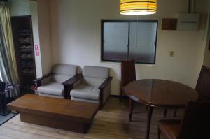 sala de estar con mesa, 2 sillas, mesa y comedor en Kusatsu Onsen Guesthouse Gyoten, en Kusatsu