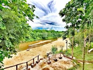 uitzicht op een rivier met bomen en een hek bij Baan NaraTawan in Suan Phung