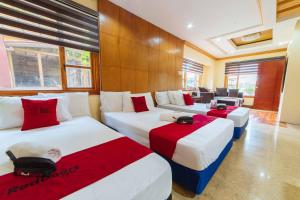 a room with three beds with red and white at RedDoorz Plus @ Starhomes Olivianville in Tarlac