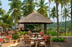 un restaurante con mesas, sillas y palmeras en Taj Green Cove Resort and Spa Kovalam, en Kovalam