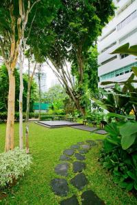 un jardin avec un chemin dans l'herbe plantée d'arbres dans l'établissement RELC International Hotel, à Singapour