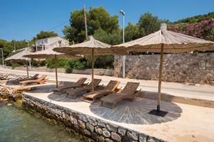 a group of chairs and umbrellas next to the water at White Rock Villa Kaprije in Kaprije