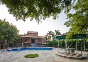 a house with a pool and a table and chairs at Wild Orchid by StayVista, 2 BHK villa with a swimming pool, spacious lawn & a gazebo for a perfect getaway in Udaipur