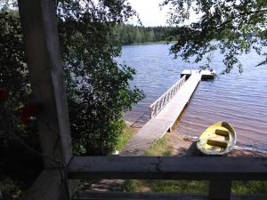 un barco está estacionado junto a un muelle en un lago en Kuvalusdream Chalet en Lintusalo