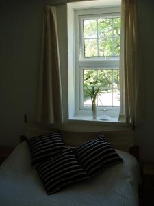 a bed with two pillows in front of a window at The Old Forge Seafood Restaurant and Bed and Breakfast in Thursford