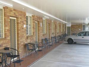 un coche aparcado en un aparcamiento con mesas y sillas en Bondi Motel en Moree