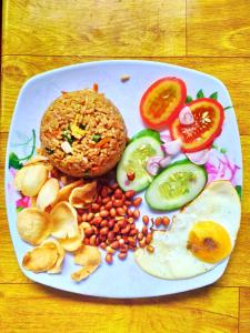 a plate of food with a fried egg and vegetables at Ira Bungalows Pulau Banyak in Alaban