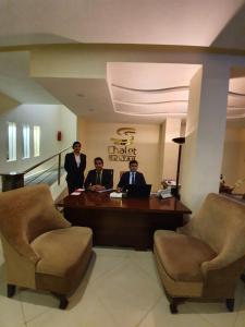 a group of men sitting at a desk in a lobby at S Chalet Multan in Multan