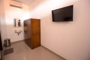 a bathroom with a flat screen tv on a wall at Arie Guest House in Nusa Penida
