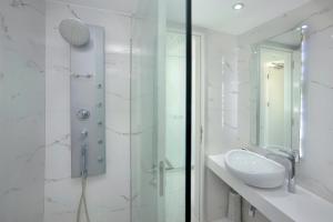 a white bathroom with a sink and a shower at Nestor Hotel in Ayia Napa