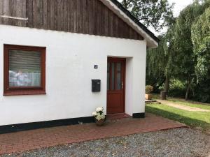 a white house with a red door and a window at Bootfahrt in Tönning