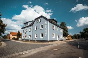un grand bâtiment bleu sur le côté d'une rue dans l'établissement Haus Seeweg, à Elsterheide
