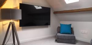 a tv on a wall with a chair and a lamp at The Three Horseshoes in Warham