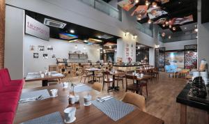 a restaurant with tables and chairs and a bar at favehotel Sidoarjo in Sidoarjo
