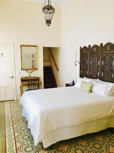 a bedroom with a large white bed and a staircase at Número 9 in Medina Sidonia