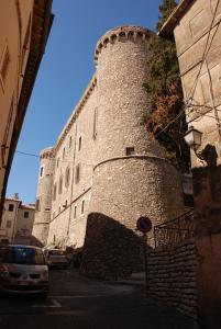 un grande edificio in pietra con una torre su una strada di Palazzetto Leonardi a San Polo dei Cavalieri