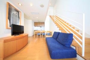 a living room with a blue couch and a staircase at TOTO Seawind Awaji in Awaji