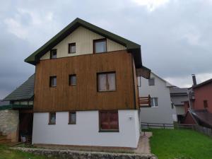 a large white house with a wooden roof at Olja Guest House in Žabljak