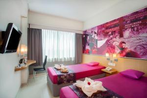 a hotel room with two beds and a tv at favehotel Manahan - Solo in Solo