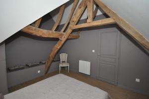 Habitación en el ático con cama y vigas de madera en Gîte de la Broderie en Bersée