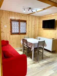 a dining room with a table and a red couch at Villaggio Turistico Camping Cervino in Antey-Saint-André