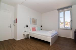 a white bedroom with a bed and a window at Apartments and Rooms Jospino in Mali Lošinj